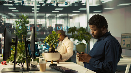 Accountant in modern office using mobile phone after inputting data on computer. Employee at work...