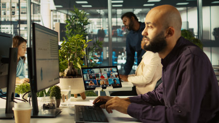 Worker in office talking with colleagues during internet videocall. Employee at work discussing with...