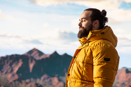 Young adventure seeker looking out at a scenic mountain range view from the top, embracing the solitude and fresh air of the nature wilderness. Sense of mindfulness and exploration.の写真素材