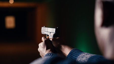 Shooting range customer reloading pistol, preparing to shoot targets during recreational sport activity. Man at firing range location loading pistol with ammunition, camera B close upの写真素材