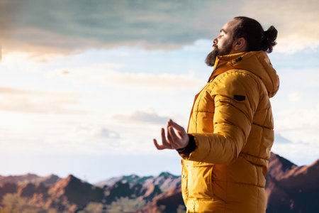 Adventure seeker doing a meditation pose on top of the mountain, successfully climbing the hill and...
