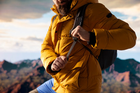 Young traveler in warm clothing reaches the peak with deep sense of satisfaction, feeling very tired...