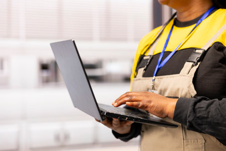 Female engineer enhances efficiency in industrial facility, using laptop to conduct quality control...