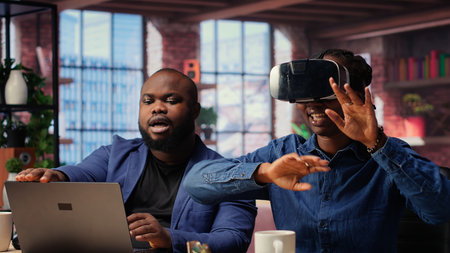 African American woman explores virtual reality using a VR headset while her partner works remotely...