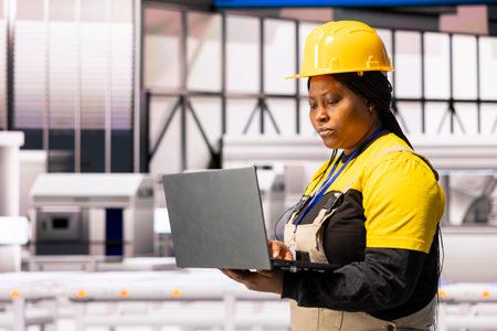 Professional technician analyzes production line featuring robotic arms and conveyor belts. The...