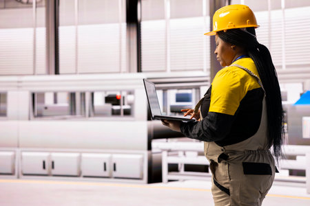 Industry 4.0 female expert monitors advanced automated system. The industrial plant digital interface supports robotic assembly lines and conveyor belts, ensuring efficient and innovative production.の写真素材