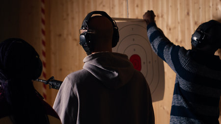 Group of shooting range customers shooting targets with pistols and rifles, learning to operate...