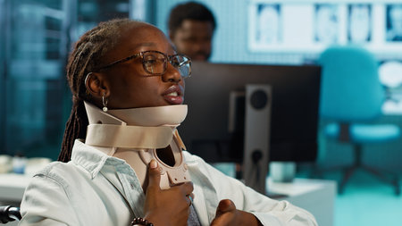 Wheelchair user with a fractured neck injury wearing cervical foam collar, talking to specialist about painkillers or advice for recovery. Young girl with spinal fracture at checkup. Camera A.の写真素材