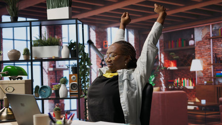 Remote employee in apartment stretching joints after sitting at desk too long. Woman in home office...