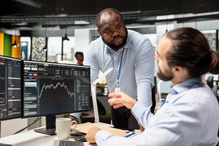 Manager supervising day trader in forex company office buying stocks to capitalize on market...