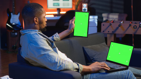 African american remote worker uses chroma key screen on gadget to work in the living room, sitting...