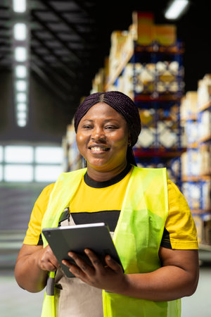 Worker wearing safety vest manages packages and process orders in compact distribution hub. This local shipping operation is in-house, supporting a growing e-commerce business.の写真素材