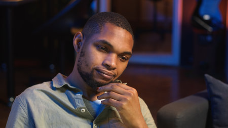 Black teleworker thinking about ways to improve his productivity, looking for new ideas for personal and professional development. Working from home on laptop, networking. Camera B.の写真素材