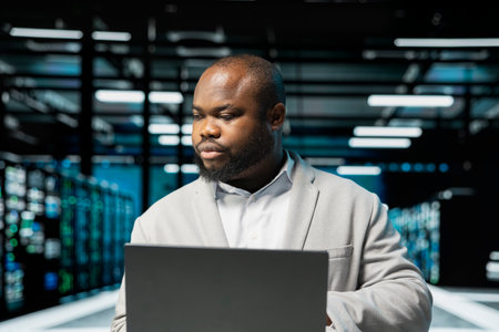 Data center admin using laptop, preparing recovery backups, doing checkup to prolong hardware life...