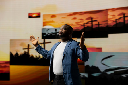 Black spiritual guy meditating on faith and serenity in a pose of worship. The background of crosses symbolizes religion and the higher power of religious devotion.の写真素材