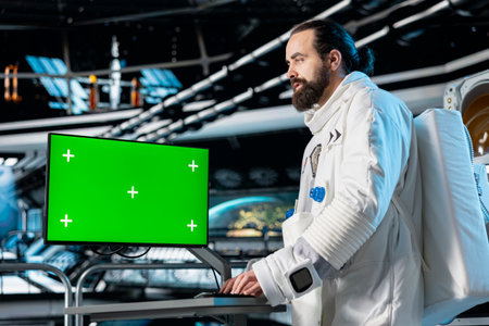 Cosmonaut verifying navigation coordinates on green screen monitor, preparing for planetary mission. Astronaut using mockup display, beginning landing procedures on solar system planetの写真素材