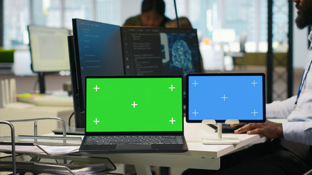 Software developer using AI on isolated screen laptop and tablet to optimize performance and...