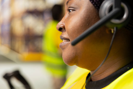 Close up of black employee handles calls on the customer service help line, assisting people with...