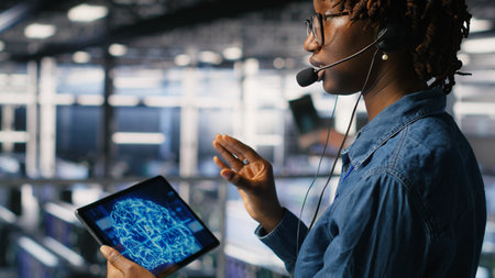Data center worker on industrial platform speaks in headset microphone while overseeing maintenance...
