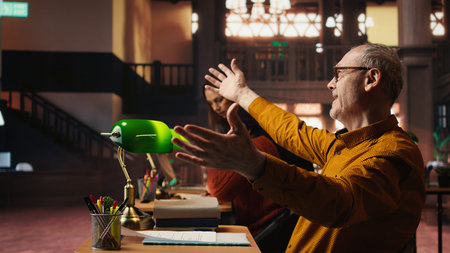 Experienced man rehearsing a theatre script in a quiet library, studying lines with commitment and emotion and practicing character development for role preparation. Acting skills.の写真素材