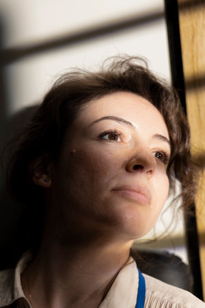 Sophisticated empowered business leader looking out the window at golden hour lighting, posing with...