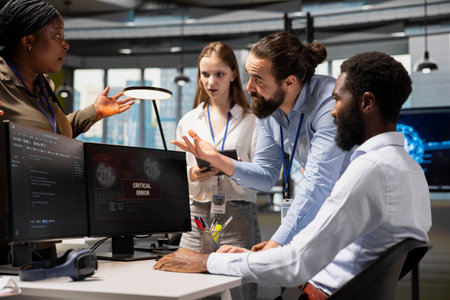 Software developers working together, resolving critical error alert on screen in tech startup...