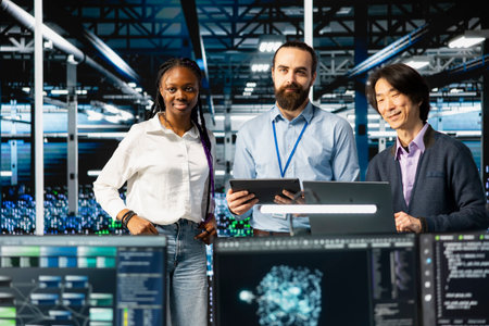 Portrait of multiethnic data center IT team running AI forecasting simulations, tracking performance. Smiling workers in diverse server hub using devices to integrate deep learning APIsの写真素材