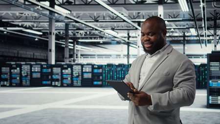 System administrator in data center workplace uses tablet to calibrate energy usage. Server farm IT...