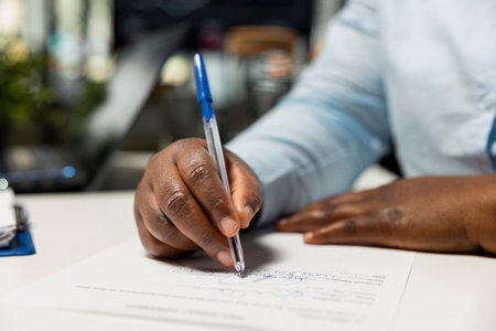 Close up of confident african american woman signing official work contract with the HR manager ensuring the form is completed. Beginning of a new and exciting business occupation.の写真素材