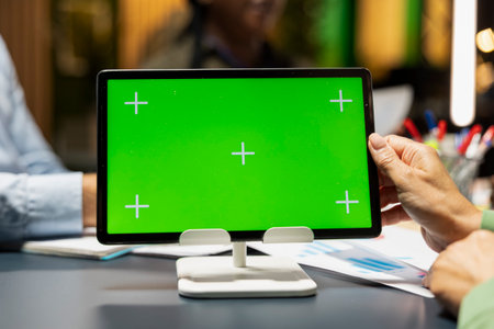Close up of business team hosting a meeting with chroma key on tablet, late night briefing conference to discuss budget updates and performance metrics. Align company objectives for vision.の写真素材