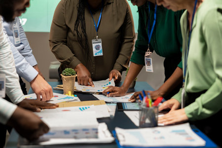 Business consultants team meeting after hours to review diagrams and assess risks, exchanging...