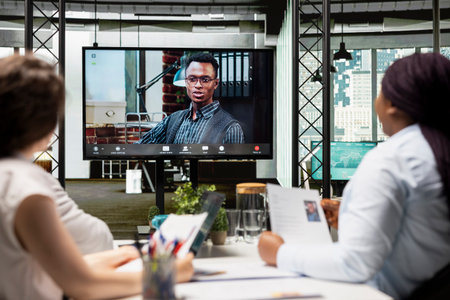 Recruiters team and male candidate engage in a video call discussion with webcam and high tech tools, reviewing the resume and assessing job search progress during a remote interview conference.の写真素材