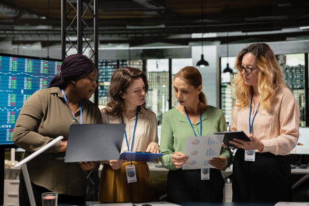 Multiethnic colleagues form a powerful team discuss business strategy, analyzing performance data on laptop and documents aligned around success, progress and shared objectives.の写真素材