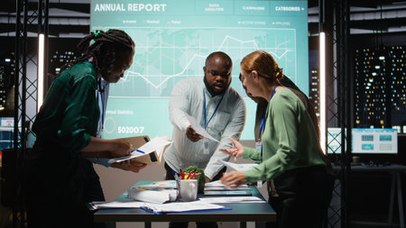 Diverse group of staff collaborating on a company briefing after hours, leveraging projections and analytics to align business goals with investors expectations in a modern corporation. Camera A.の写真素材
