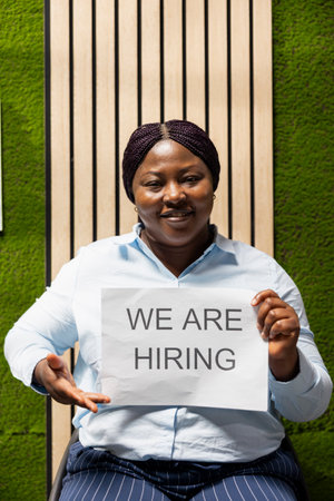 Black business person from the hiring team displaying advertisement banner promoting open positions,...