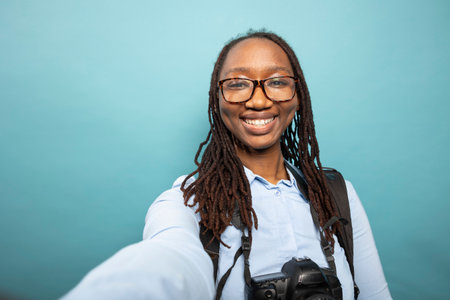 POV of trendy black woman grinning at camera while filming herself in a studio. African american...