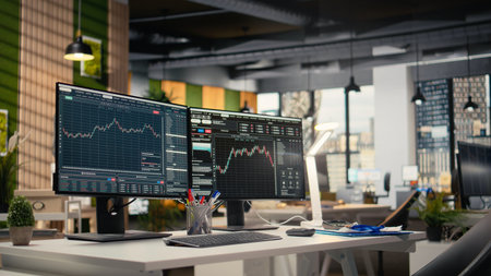 Stock exchange metrics insights displayed on computer screens in hedge fund business office. PC monitors on desk with financial software interface visible in forex company workspaceの写真素材