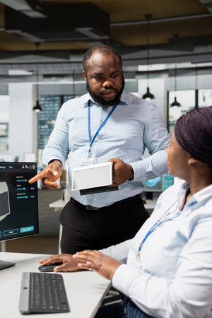 RD department manager checking work of employee on clean energy solar device project. Green tech company team leader and expert design solar gadget prototype to reduce environmental impactの写真素材