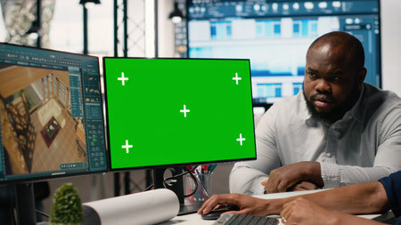 Real estate colleagues evaluates blueprints next to chroma key screen, zoning regulations and property investment opportunity for housing and residential area market growth.の写真素材