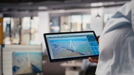 Close up of technician using tablet to work on futuristic wind turbine designed for clean energy output. Worker swiping on touchscreen device, designing cutting edge VAWT innovation, camera Aの写真素材