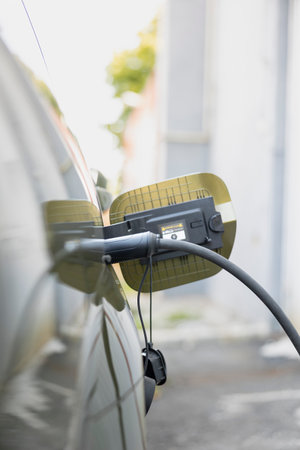 Close up of parked electric car charging port flap open to recharge depleted battery. Vehicle inlet port of EV automobile opened in preparation green electricity resupplyの写真素材