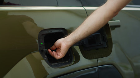 Close up of driver connecting EV plug to electric car to recharge it, concept of zero emissions technology. Man charging electric vehicle at EVSE station, showcasing green energy transportationの写真素材