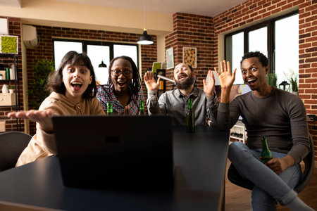 Happy multiethnic group looking at laptop with excitement, cheerfully greeting longtime acquittance on videoconference. Diverse friends waving at device screen with joyful surprise during virtual callの写真素材