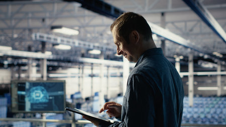 Jolly IT professional monitors server room activity using tablet in facility. Happy data center...