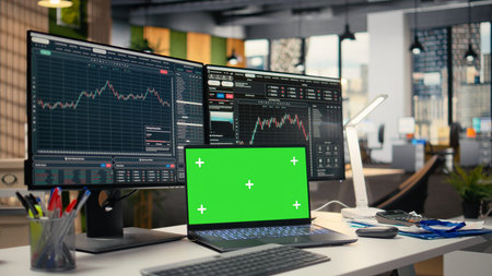 Stock market metrics diagrams displayed on green screen laptop in prop firm office. Workstation in forex company workspace with live financial data visible on mockup notebookの写真素材