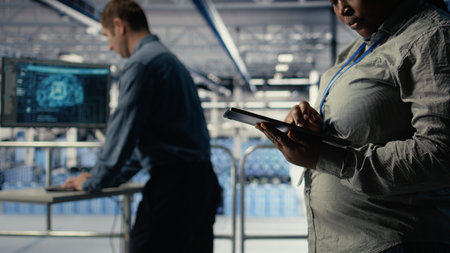 Data center programmers check AI dashboard using tablet, doing systems review. Server hub coworkers...