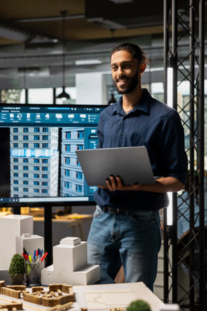 Middle eastern engineer finalizing plans for land acquisition in a modern office using laptop, working toward residential project success through careful city planning and investment strategy.の写真素材