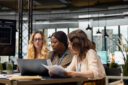 Team of career focused women aligning analytics and objectives, reviewing financial performance data to lead company toward success in a smart and collaborative work environment.の写真素材