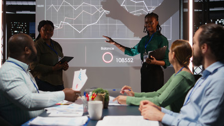 Diverse business consultants reviewing targets and proposals for a project agenda, examining data insights on a projection board with shareholders after hours in a briefing session. Camera A.の写真素材