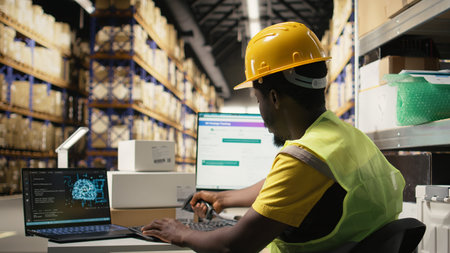 Black employee works with AI tools to enhance package tracking efficiency, using machine learning and parcel tracking info to ensure seamless distribution operations in warehouse. Camera A.の写真素材